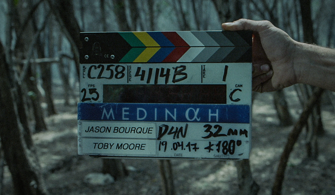 Original Medinah production slate held in a wooded setting